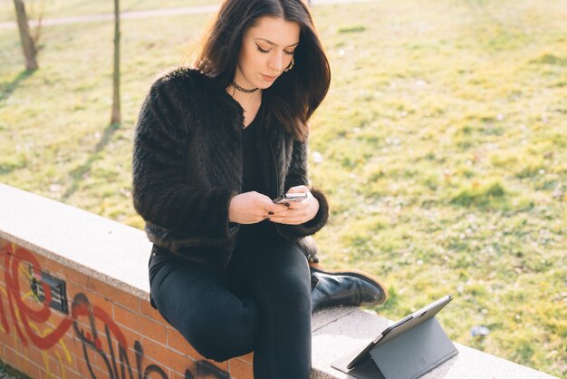 belle jeune femme à l&#39;aide de tablette et smartphone