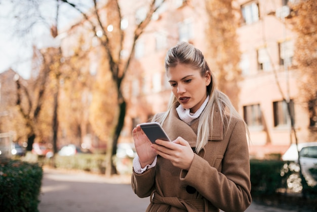 Belle jeune femme à l&#39;aide d&#39;un téléphone intelligent à l&#39;extérieur.