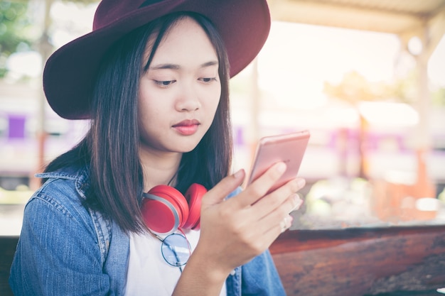 Belle jeune femme à l&#39;aide de voyage app sur un téléphone portable dans ses mains