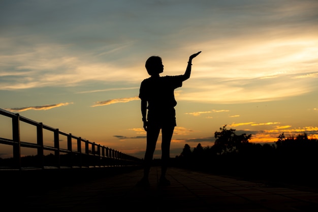 Belle jeune femme a l'air pleine d'espoir à ses mains au coucher du soleil.concept succès en main