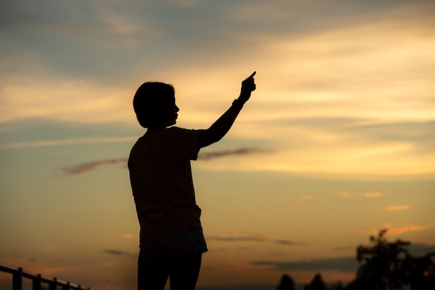 Belle jeune femme a l'air pleine d'espoir à ses mains au coucher du soleil.concept succès en main