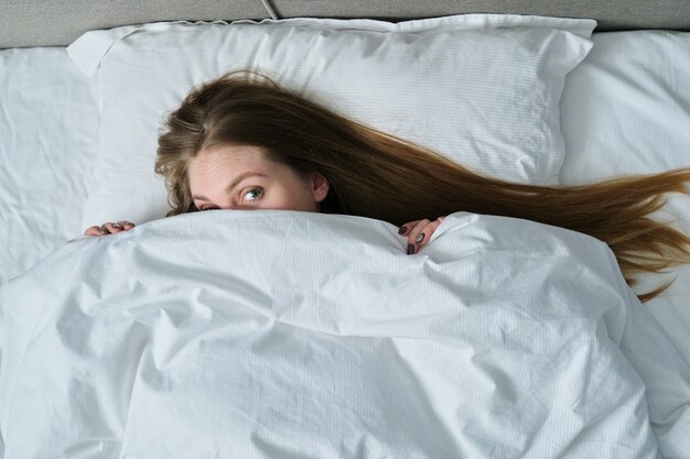 Belle jeune femme allongée sur l'oreiller dans son lit