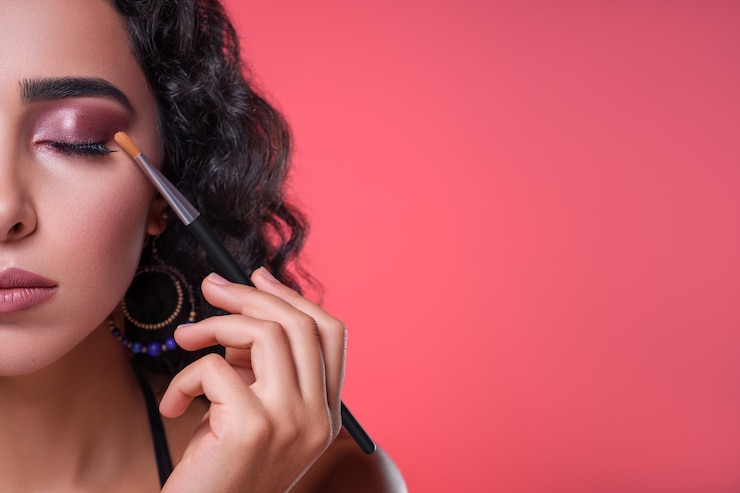 Photo belle jeune femme appliquant le maquillage