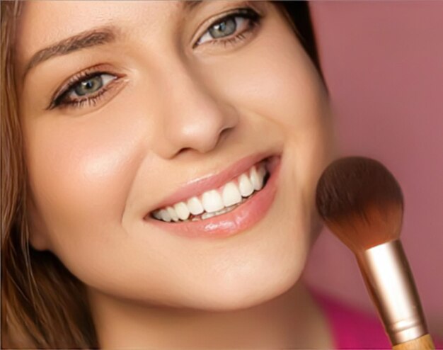 Belle jeune femme appliquant un produit cosmétique en poudre avec une brosse de maquillage en bambou beauté maquillage et soins de la peau modèle visage portrait sur fond rose