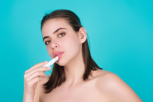 Une belle jeune femme applique du rouge à lèvres sur les lèvres couleur d'arrière-plan de studio fille sexy appliquée