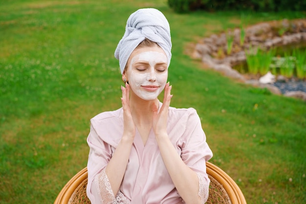 Belle jeune femme a appliqué un masque sur son visage avec une serviette sur la tête