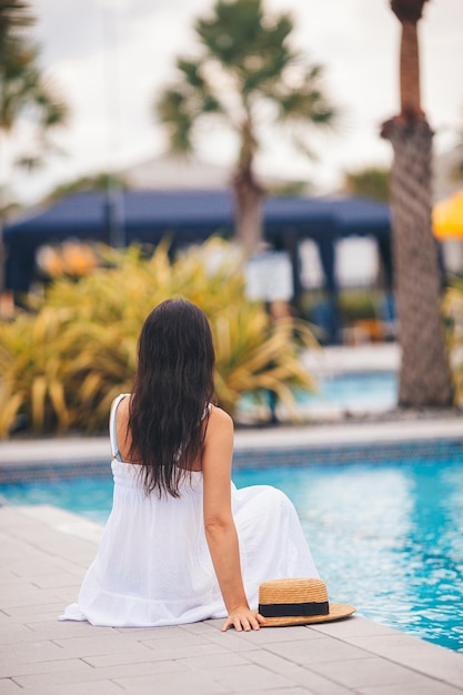 Photo une belle jeune femme apprécie les vacances d'été dans une piscine de luxe à l'infini.