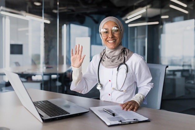 Une belle jeune femme arabe un médecin musulman est assis dans le bureau au bureau dans un hijab il