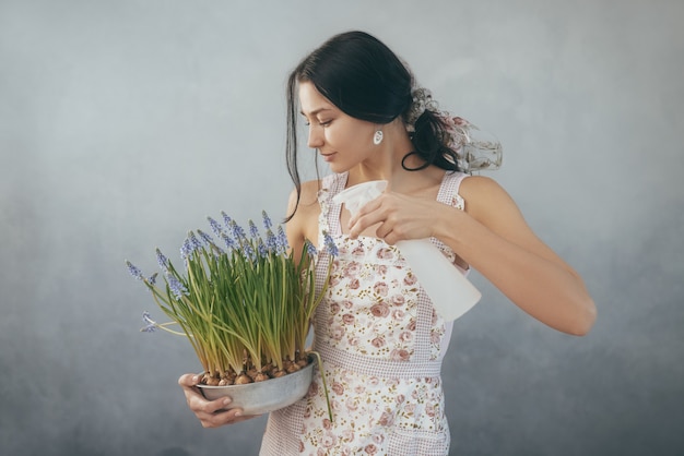 Belle jeune femme arrosage des fleurs de printemps en pot de fleurs