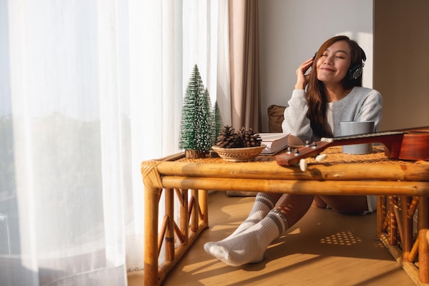 Une belle jeune femme asiatique aime écouter de la musique avec un casque à la maison des concepts de bonheur et de relaxation