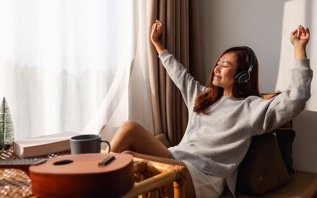 Une belle jeune femme asiatique aime écouter de la musique avec un casque à la maison