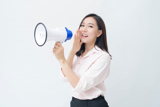 Une belle jeune femme asiatique annonce par mégaphone sur fond blanc