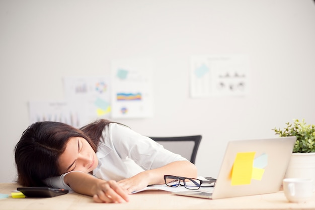 Belle jeune femme asiatique au repos au bureau quand terminer le travail, concept de travail de femme