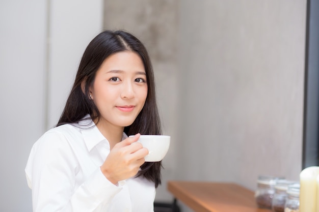 Belle jeune femme asiatique, boire du café et sourire le matin au café