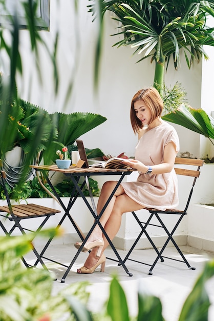 Belle jeune femme asiatique buvant le matin au café et remplissant le planificateur d'idées