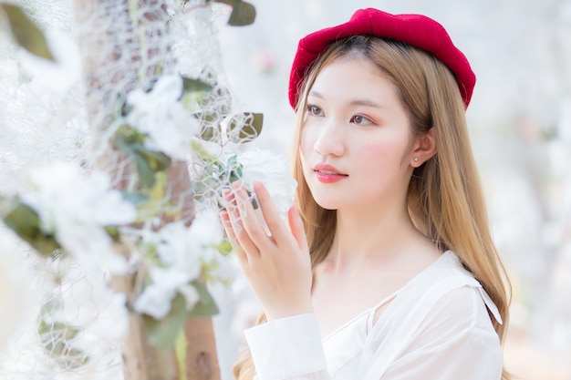 La belle jeune femme asiatique cherche une fleur blanche dans le jardin naturel.