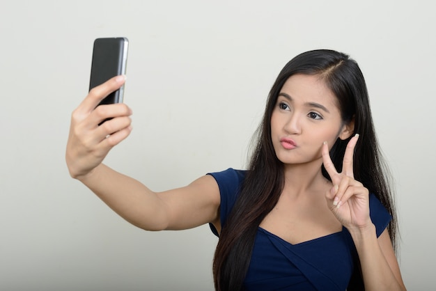 Belle jeune femme asiatique contre le mur blanc