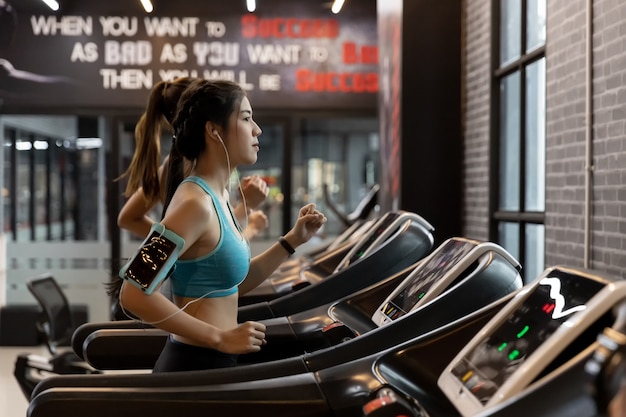 Belle jeune femme asiatique en cours d&#39;exécution sur un tapis roulant à la gym.