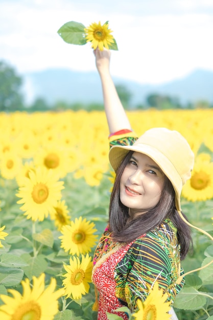 Belle jeune femme asiatique dans un champ de tournesols dans une robe décontractée colorée