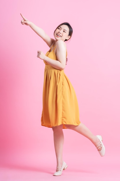 Belle jeune femme asiatique dansant sur fond rose