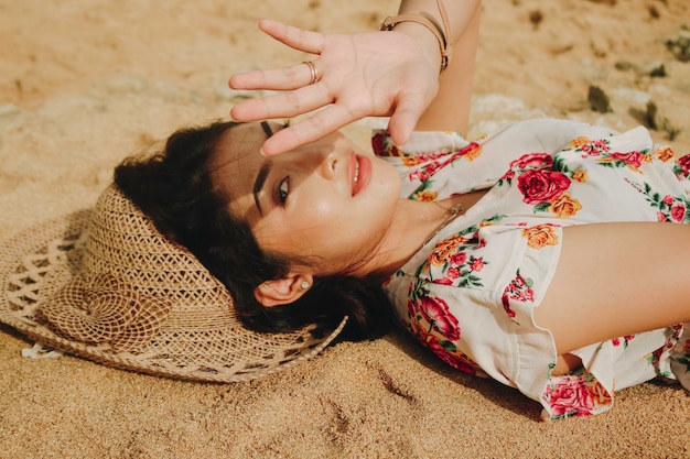 Une belle jeune femme asiatique éblouie par la lumière allongée sur le sable de la plage