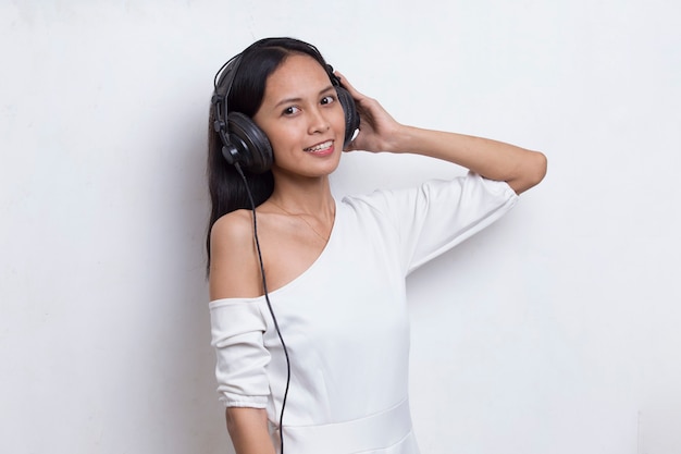 Belle jeune femme asiatique écoutant de la musique isolée sur fond blanc