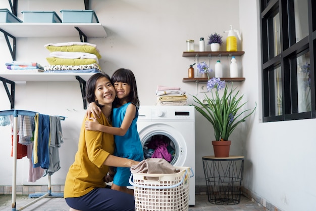 Belle jeune femme asiatique et enfant fille petite aide font la lessive à la maison.
