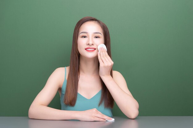 Belle jeune femme asiatique enlève le maquillage avec un tampon de coton cosmétique blanc Soins de la peau du visage