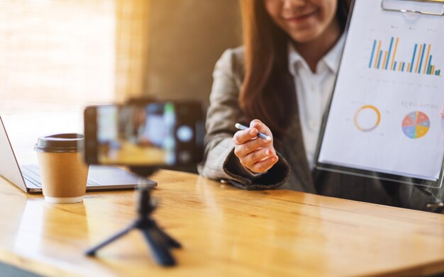 Une belle jeune femme asiatique enseigne la classe affaires en ligne avec un ordinateur portable sur la table