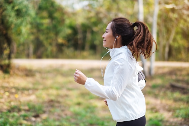 Une belle jeune femme asiatique faisant du jogging dans le parc de la ville le matin