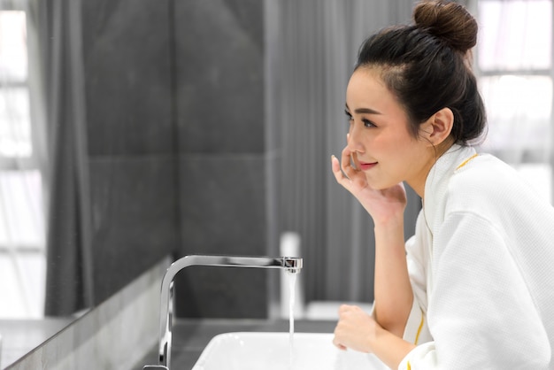 Belle Jeune Femme Asiatique, Laver Le Visage Propre Avec De L'eau Et Souriant Devant Le Miroir Dans La Salle De Bain. Beauté Et Spa. Peau Fraîche Parfaite