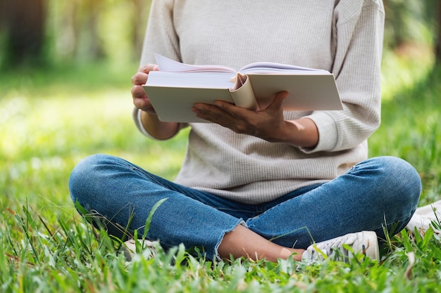 Une belle jeune femme asiatique lisant un livre assis dans le parc