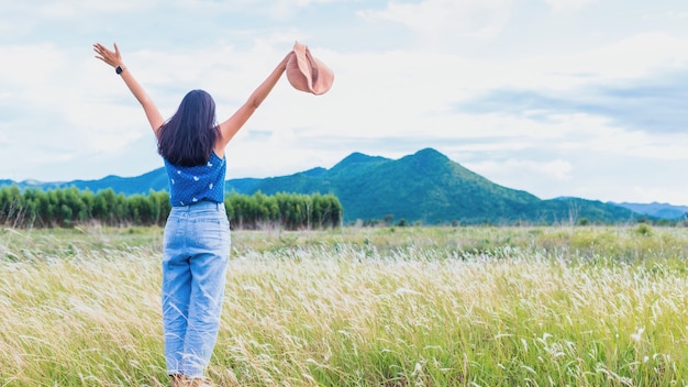 Belle jeune femme asiatique marchant et prenant une photo en arrière-plan de paysage de champ de fleurs de prairie.