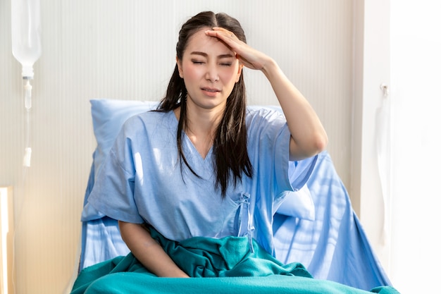 Belle jeune femme asiatique maux de tête patient sur la chambre d'hôpital.