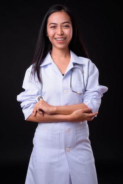 belle jeune femme asiatique médecin contre le mur noir