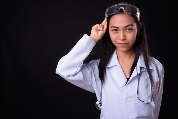 Belle jeune femme asiatique médecin en tant que scientifique avec des lunettes de protection contre le mur noir