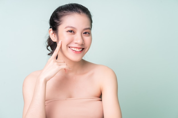 Belle jeune femme asiatique à la peau fraîche. Soins du visage, traitement du visage, peau de beauté femme isolée sur fond vert. cosmétologie, beauté de la peau et cosmétique