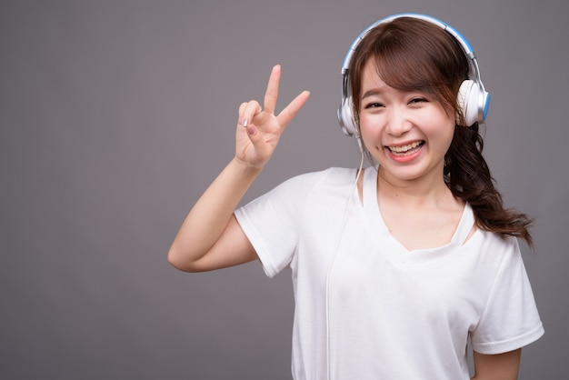 Belle jeune femme asiatique portant des écouteurs pour la musique