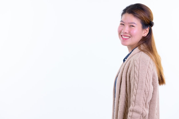 Belle jeune femme asiatique prête pour l'hiver isolé contre le mur blanc