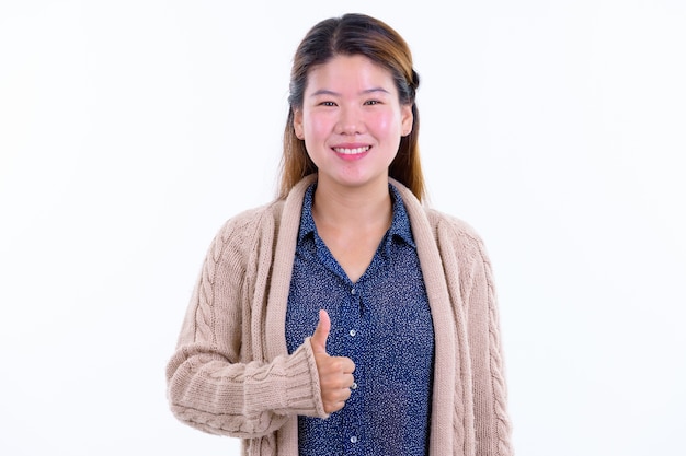 Belle jeune femme asiatique prête pour l'hiver isolé contre le mur blanc