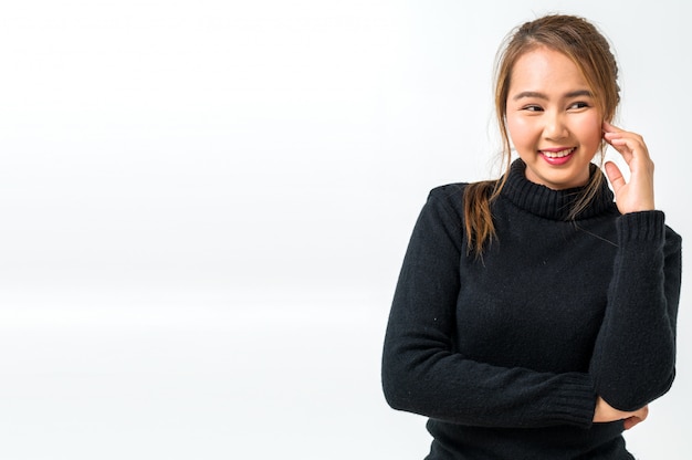 Belle jeune femme asiatique avec pull noir sur mur blanc