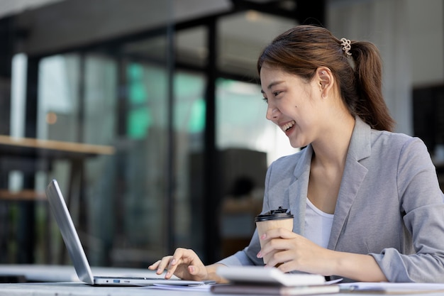 Belle jeune femme asiatique regardant des informations sur une image de concept d'ordinateur portable d'une femme d'affaires asiatique travaillant une femme d'affaires de démarrage intelligente et moderne