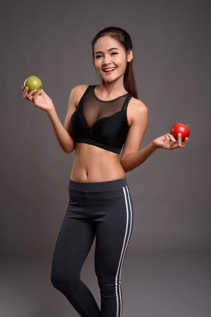 Belle jeune femme asiatique de remise en forme avec une taille mince tenant la pomme