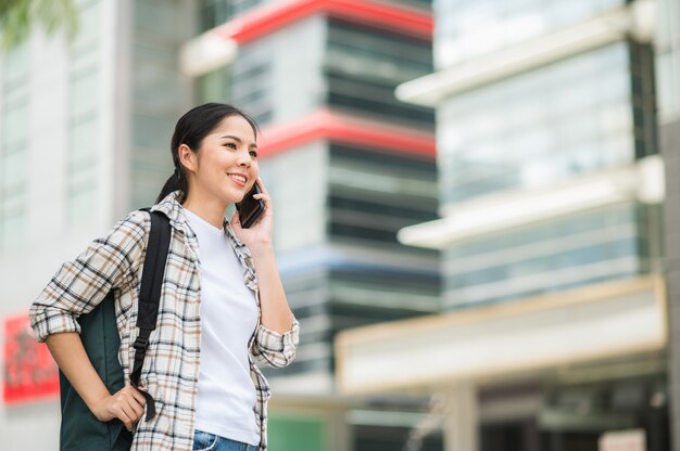 Belle jeune femme asiatique avec sac à dos à l'aide de smartphone