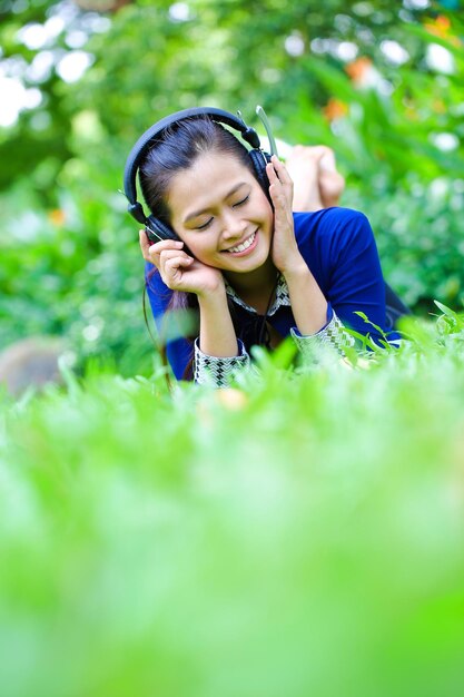 Belle jeune femme asiatique se coucher sur l'herbe écouter de la musique