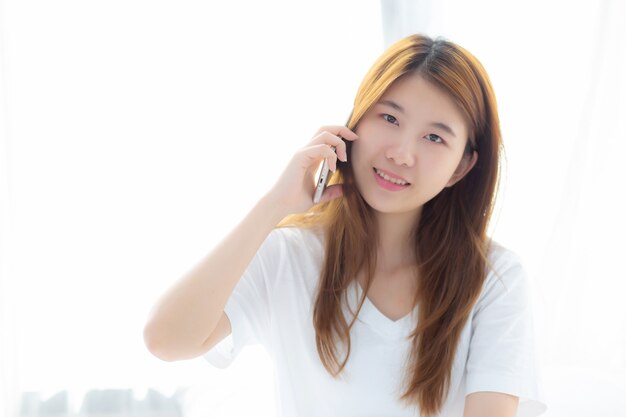 Belle jeune femme asiatique souriante assise et se détendre sur le lit