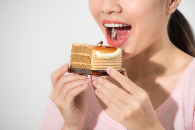 Belle jeune femme asiatique souriante avec un gâteau au chocolat isolé sur fond blanc.