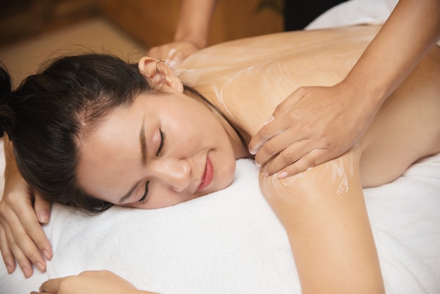 Belle jeune femme asiatique sourire obtenir un salon de massage spa sur lit blanc
