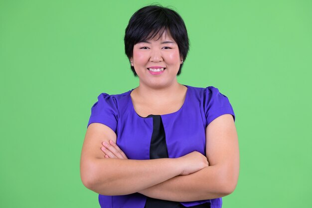 Belle jeune femme asiatique en surpoids contre la clé de chrominance avec mur vert