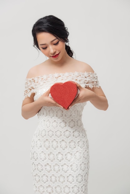 Belle jeune femme asiatique tenant une boîte-cadeau d'amour isolée sur fond blanc